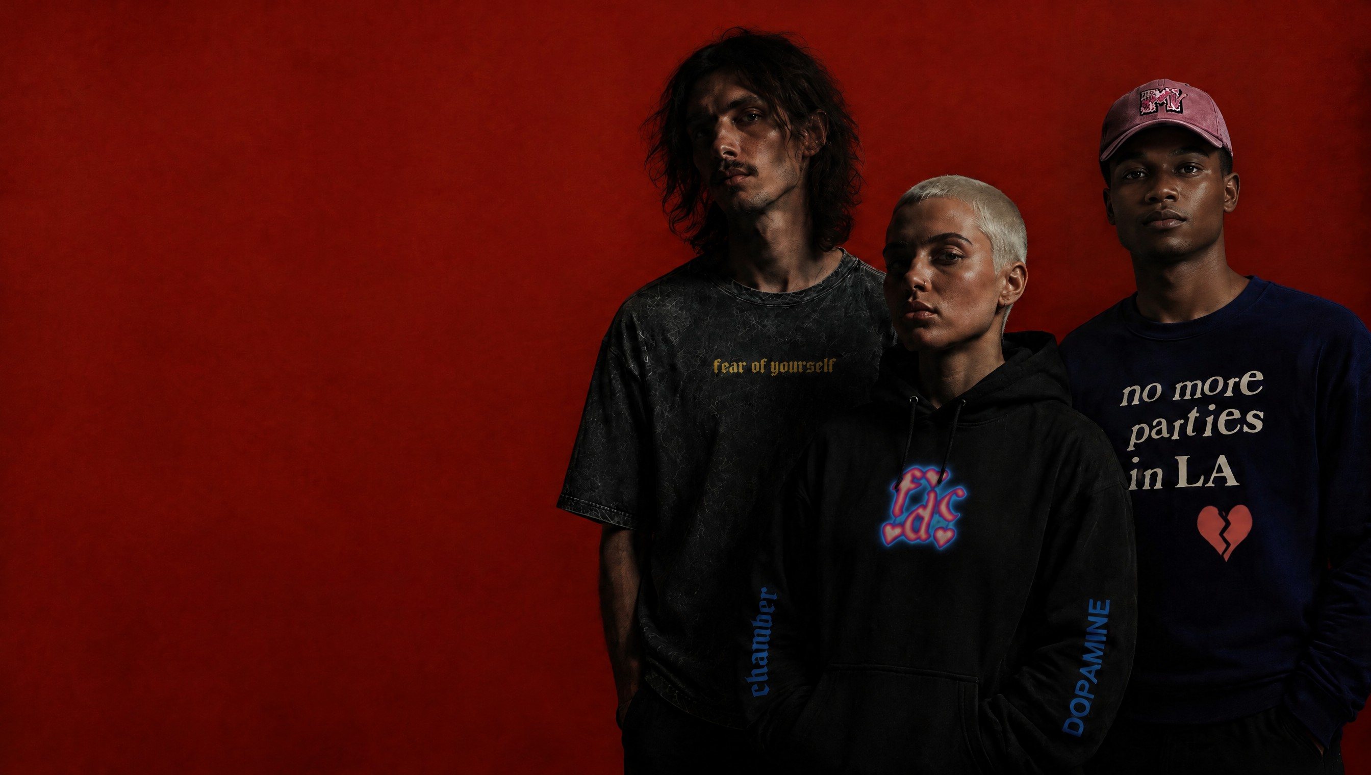Tres modelos con prendas de fear of yourself sobre fondo rojo